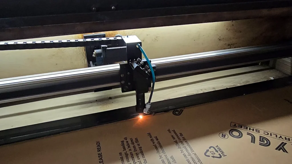 Laser head cutting an acrylic sheet, with sparks