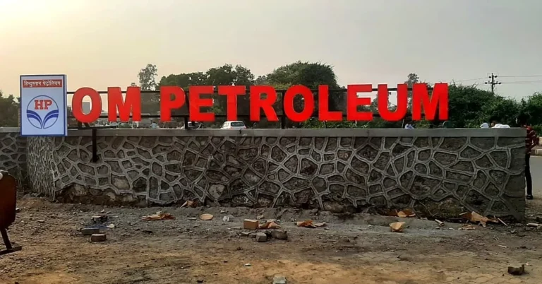 OM PETROLEUM in red 3D LED acrylic letters on a metal frame along the top of a stone wall, with a lit HP logo board at the end, at the fuel station at Ambegaon Budruk, Pune