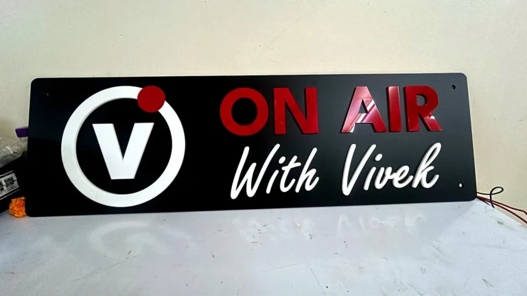 The ON AIR With Vivek board: a white V logo with a red dot, ON AIR in glossy red and With Vivek in white script, raised on matte black acrylic