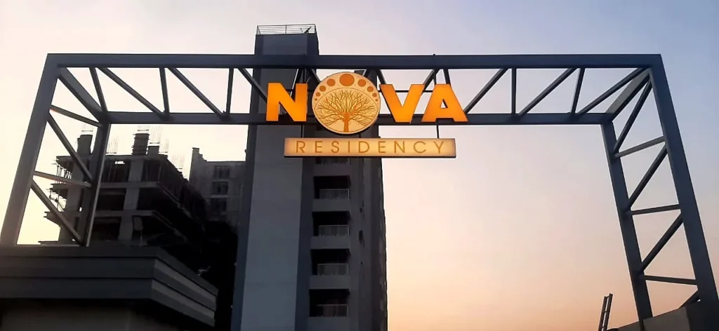 NOVA RESIDENCY in lit channel letters on the steel gate arch of Rathi Developer’s Nova Residency site at dusk, Tathawade