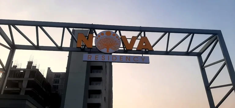 The Nova Residency gate arch from further back at dusk, with the building under construction behind it