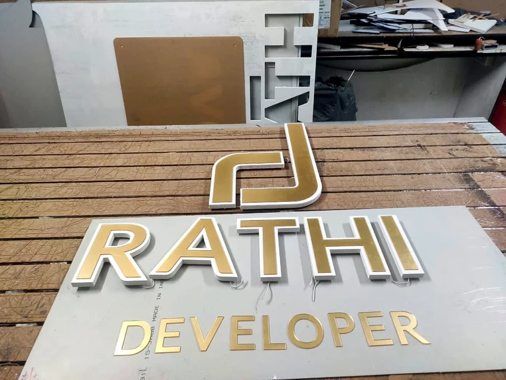 The Rathi Developer logo letters in our workshop: gold mirror acrylic faces on white WPC bases, before fitting