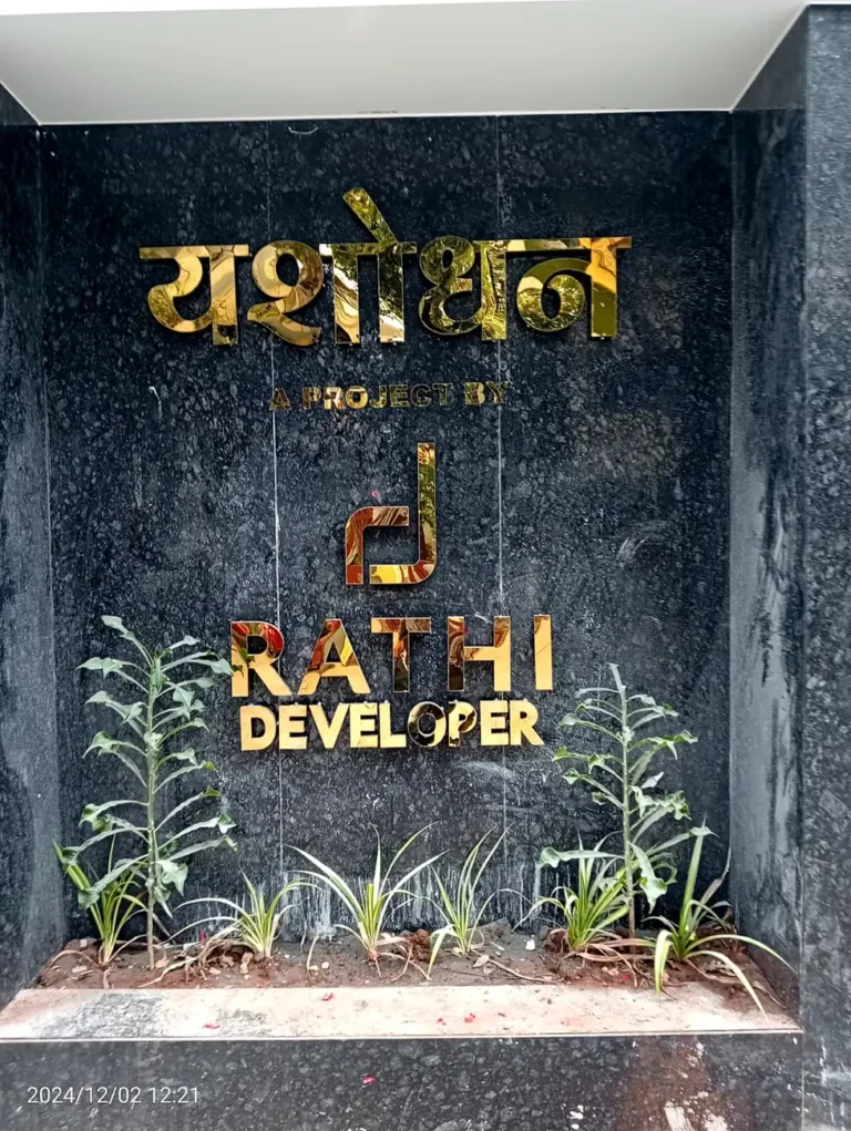The Yashodhan gate wall by day: gold steel letters on black granite