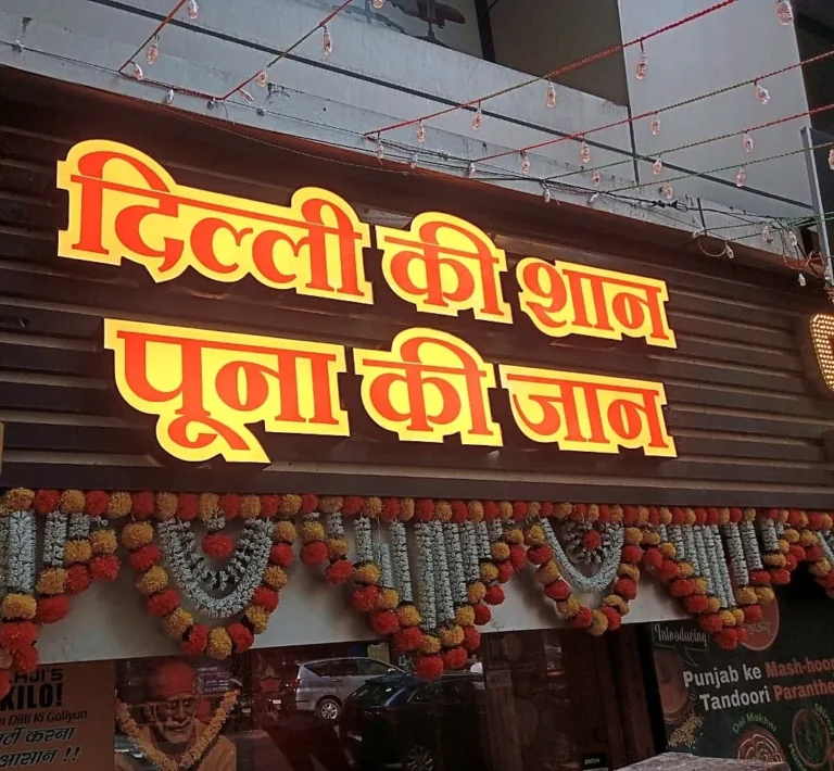 Shahji Paratha House: Delhi ki shaan, Poona ki jaan in orange 3D LED acrylic letters, lit, above the garlanded shop front