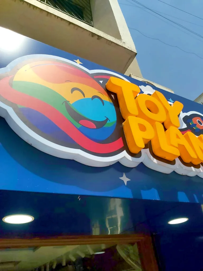 Close-up of the TOY PLANET logo: the printed planet plate with white sides and the raised orange letters on top