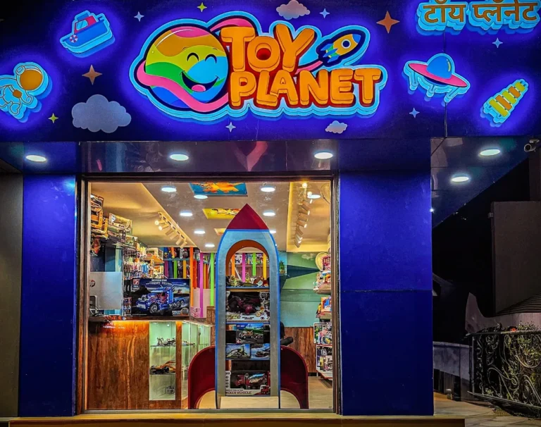 The Toy Planet front at night, letters and shapes glowing (photo from Toy Planet’s Google listing)