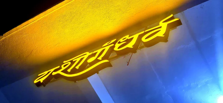 Close-up of the lit Yashogandharva letters at night